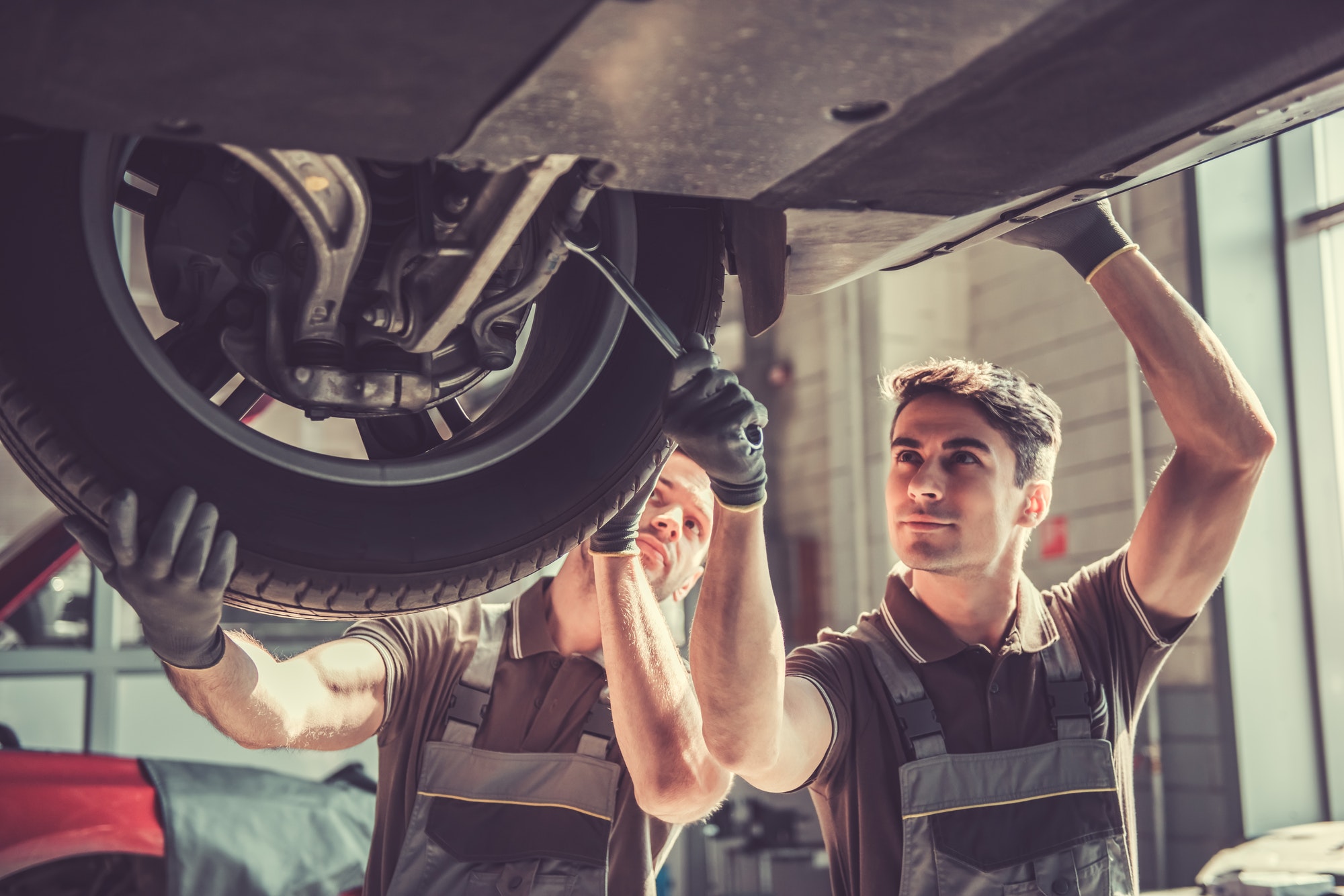 Two mechanics working on car suspension