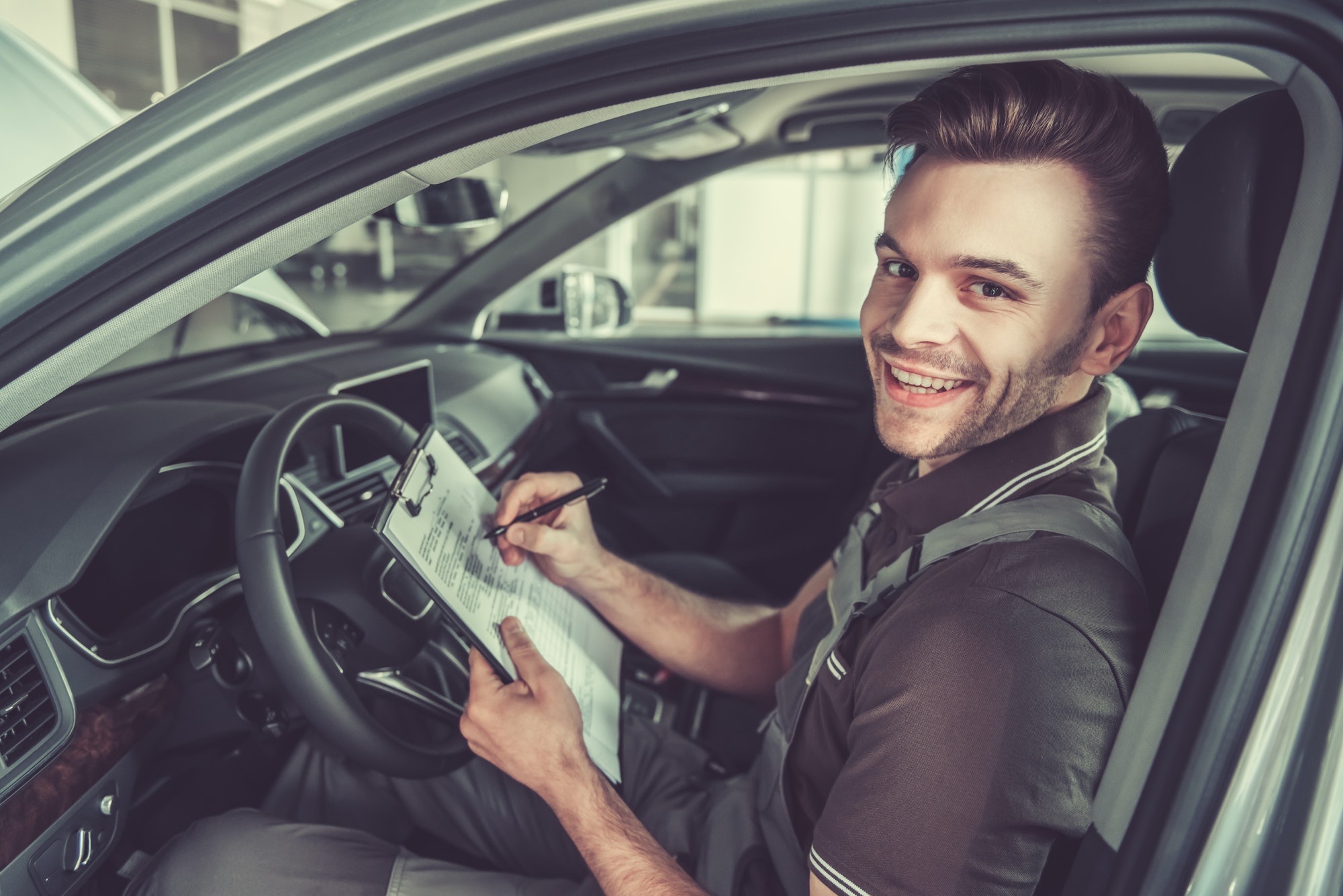 Smiling mechanic filling out vehicle inspection form