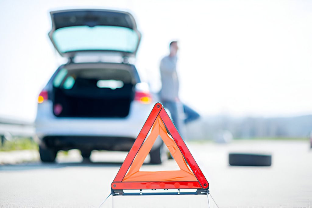 Car broken down with warning triangle