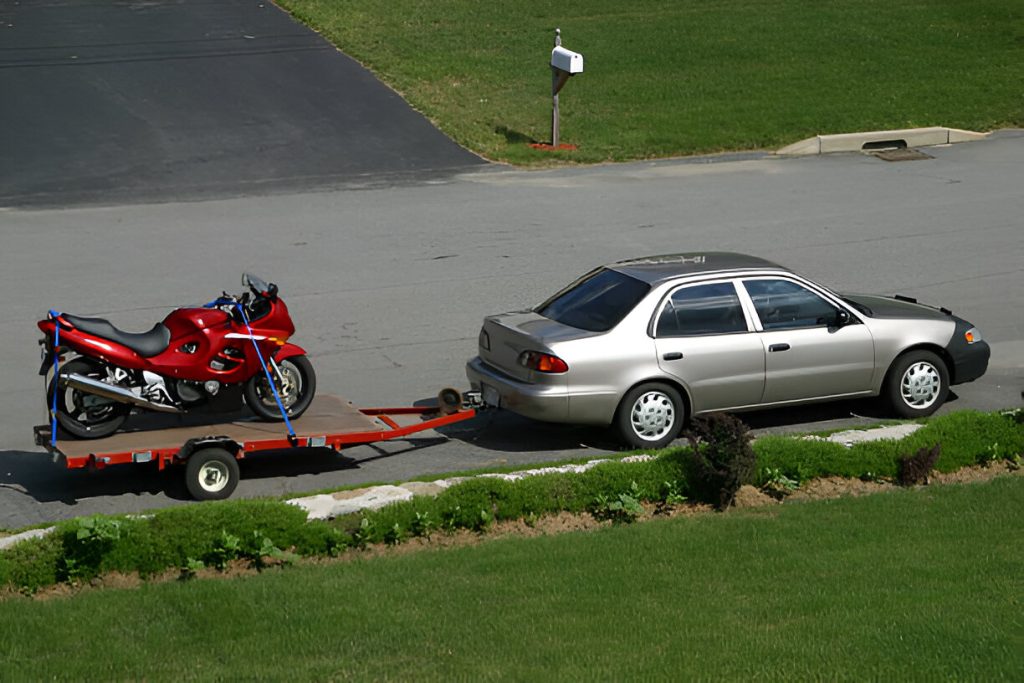 Car towing motorcycle on trailer