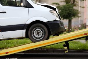 Damaged van being loaded onto tow truck after accident