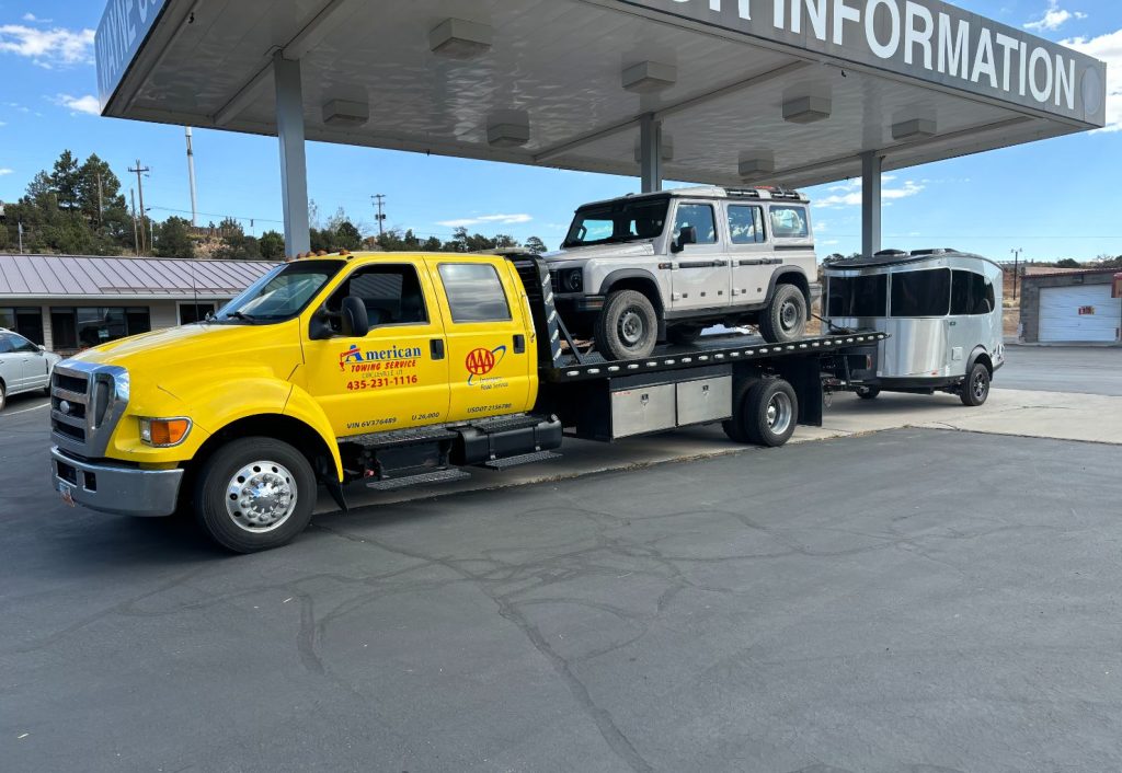 Tow truck hauling a lifted white pickup at a gas station in Circleville, UT.