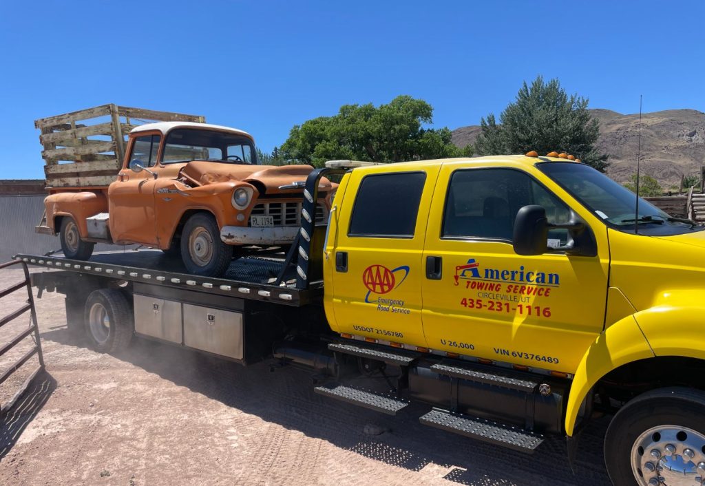 Tow truck transporting a classic vintage orange pickup truck.