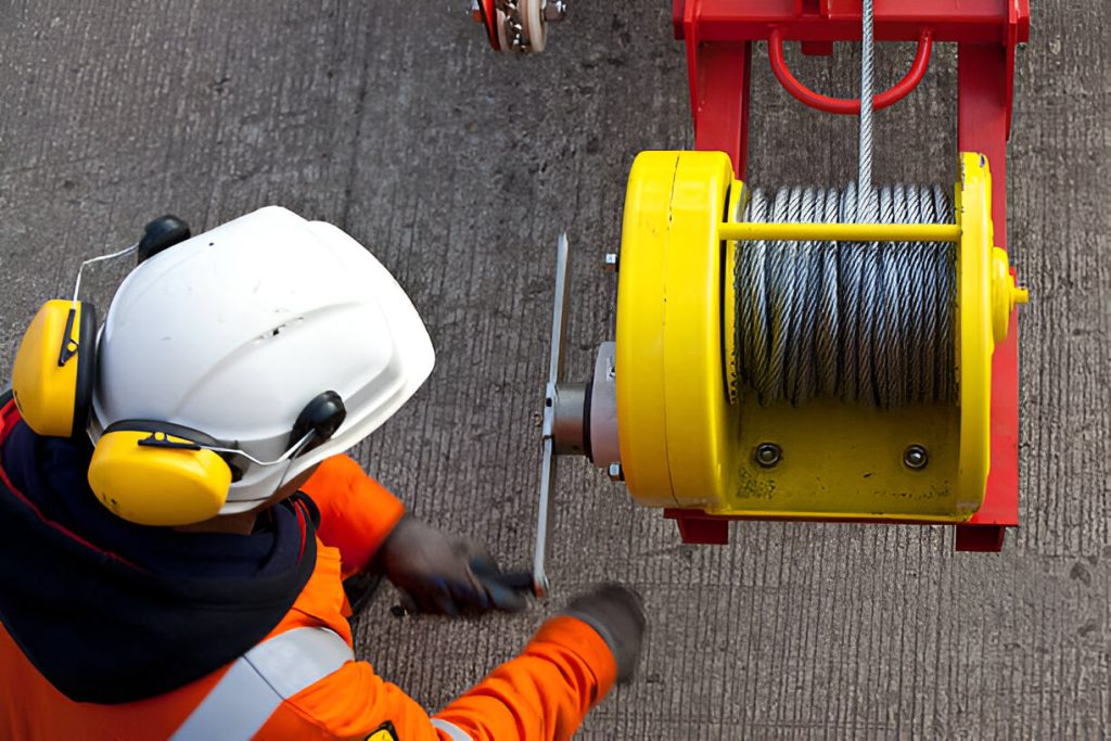 Worker operating heavy winch machinery