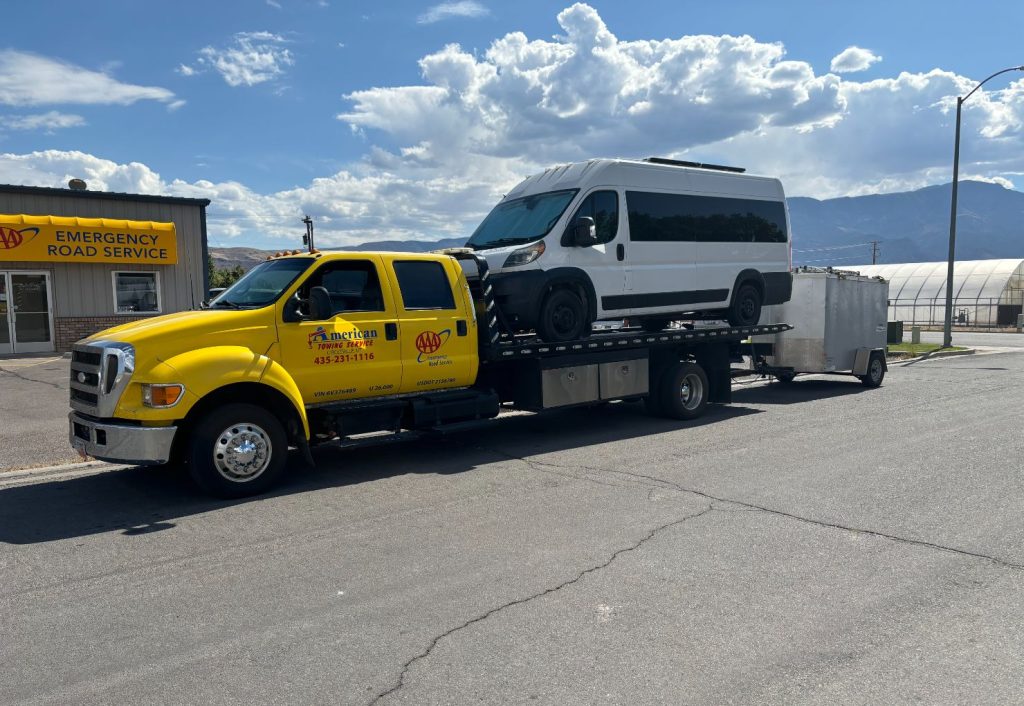Yellow tow truck transporting a large black pickup truck in Circleville, Utah.