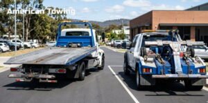 Two American Towing tow trucks parked on the side of a road