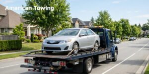 American Towing truck carrying a silver sedan; relevant to towing cost per mile.