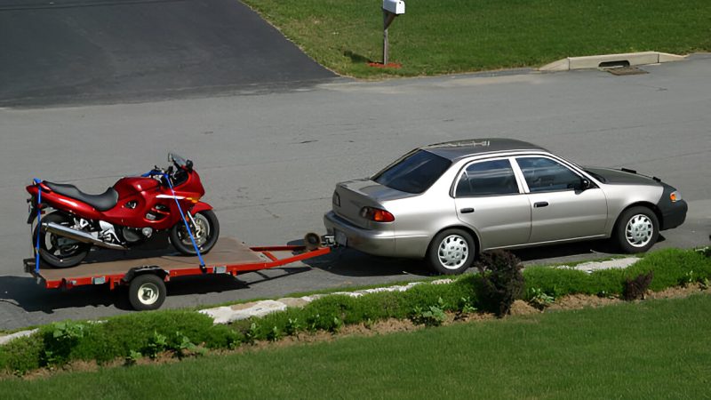 Car towing motorcycle on trailer
